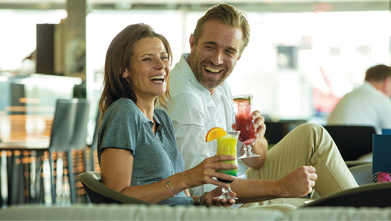 Man and woman laughing as they enjoy their cocktails in the surrounds of a modern bar and lounge space