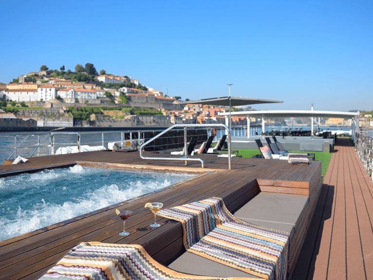 An outdoor pool located on the sun-drenched top deck of the Scenic Azure cruise ship, providing a view of the Douro River in Portugal.