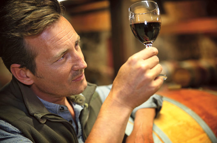 Man holding up and inspecting a glass of red wine