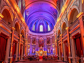 Guests watching a performance, surrounded by the stunning baroque interior of the Trinity Chapel in Lyon.