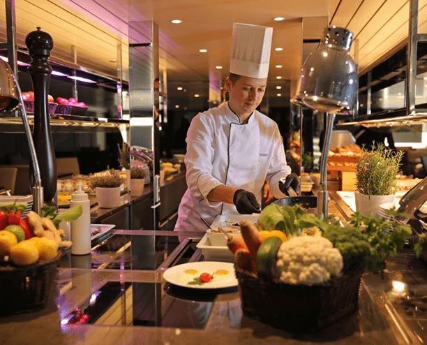 A Chef preparing food in the kitchen of Crystal Dining on a Scenic cruise ship.