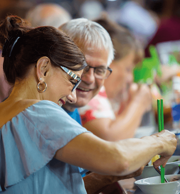 Older couple smiling and enjoying Vietnamese noodle soup at a local restaurant.