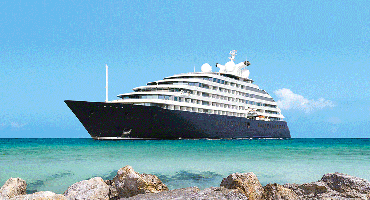 Scenic Eclipse luxury yacht in turquoise ocean water near a rocky shore